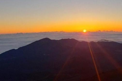 Sunrise over a mountain range with clouds and an orange sky.