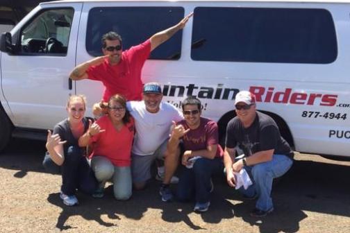 Group of six people posing in front of a white van with 'Mountain Riders' text.