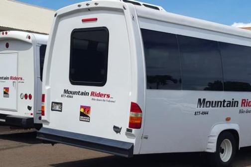 Two white tour buses with 'Mountain Riders' logo parked in a lot.